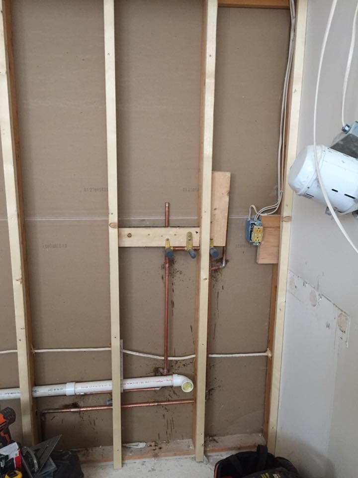 A wall with pipes and wires coming out of it.