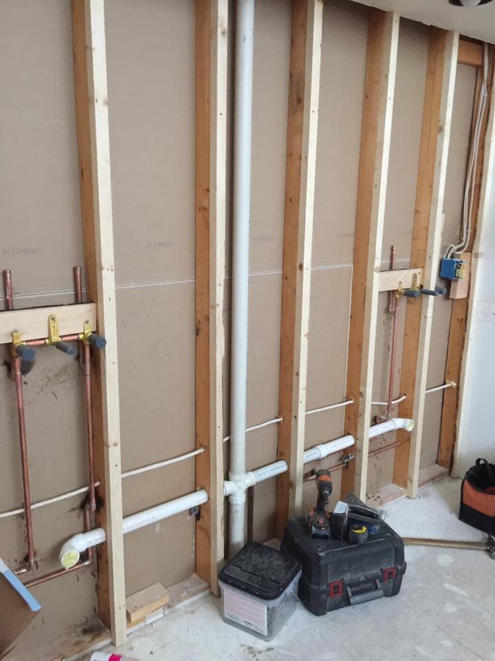 A room under construction with pipes and a toolbox on the floor.