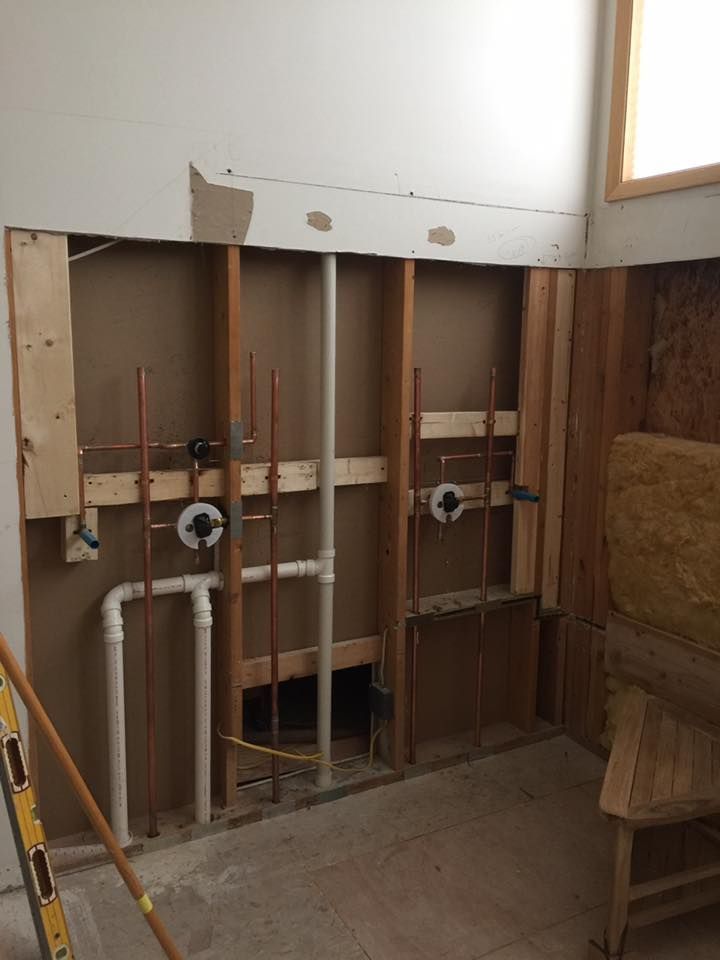 A bathroom under construction with pipes coming out of the wall.