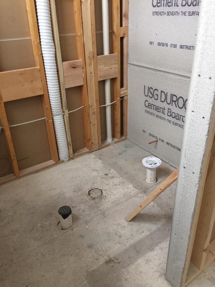 A bathroom under construction with a toilet and a drain.