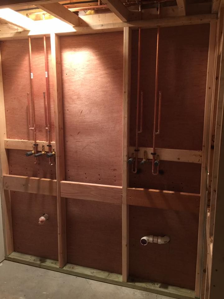 A bathroom under construction with copper pipes coming out of the wall.