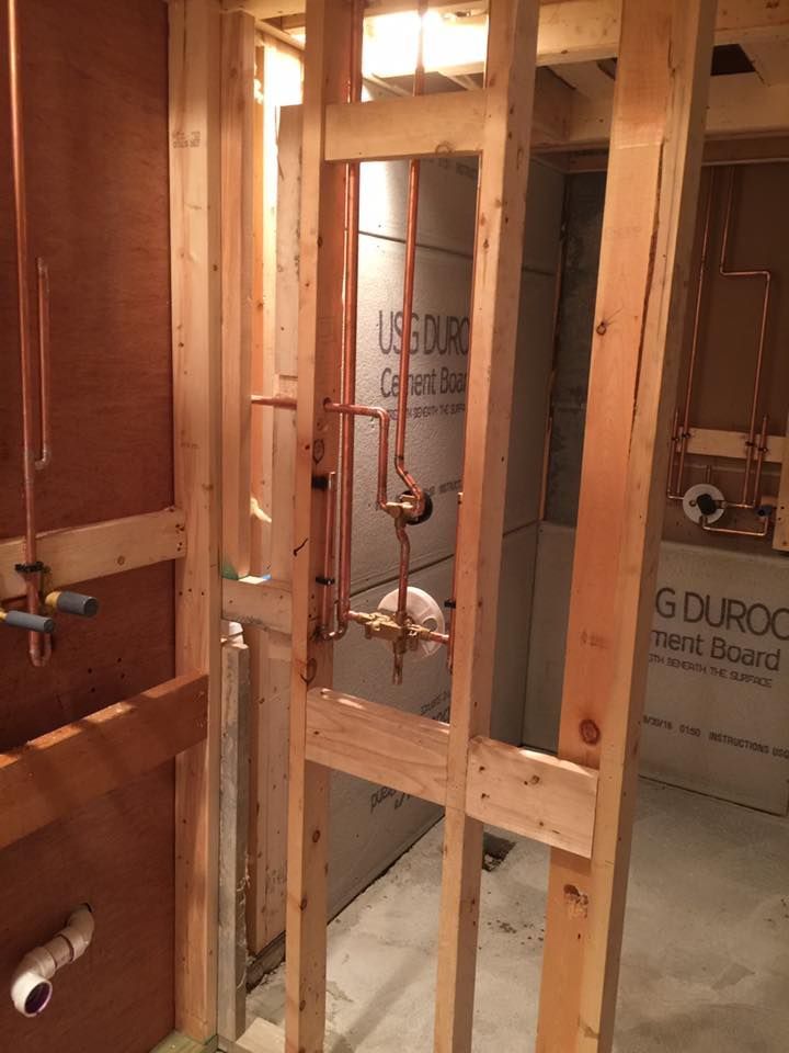A bathroom under construction with wooden walls and copper pipes.