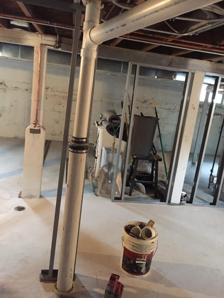 A bucket of paint is sitting on the floor in a basement.