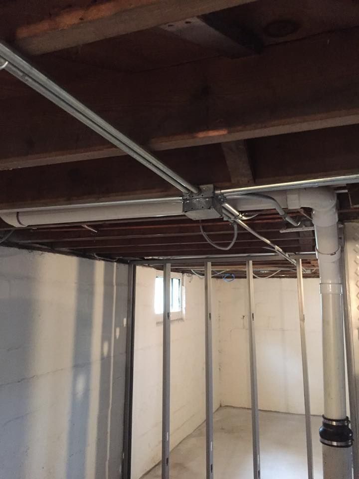 A basement with pipes and wires hanging from the ceiling