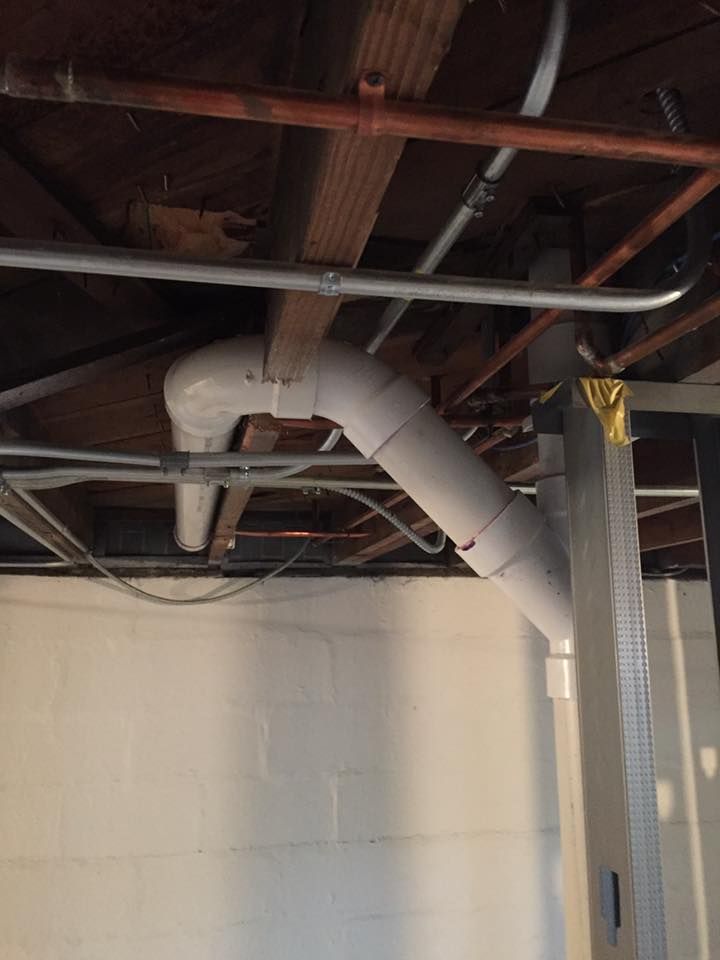 A basement with a lot of pipes and wires hanging from the ceiling.