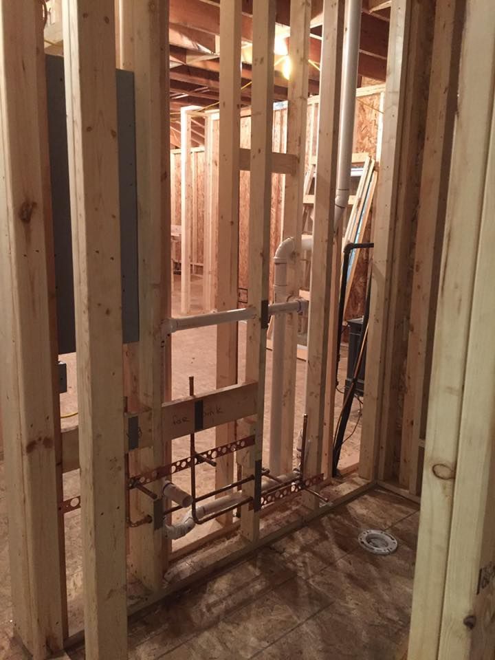 A room under construction with wooden beams and pipes.