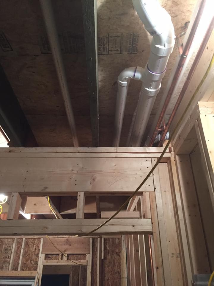A house under construction with pipes coming out of the ceiling.