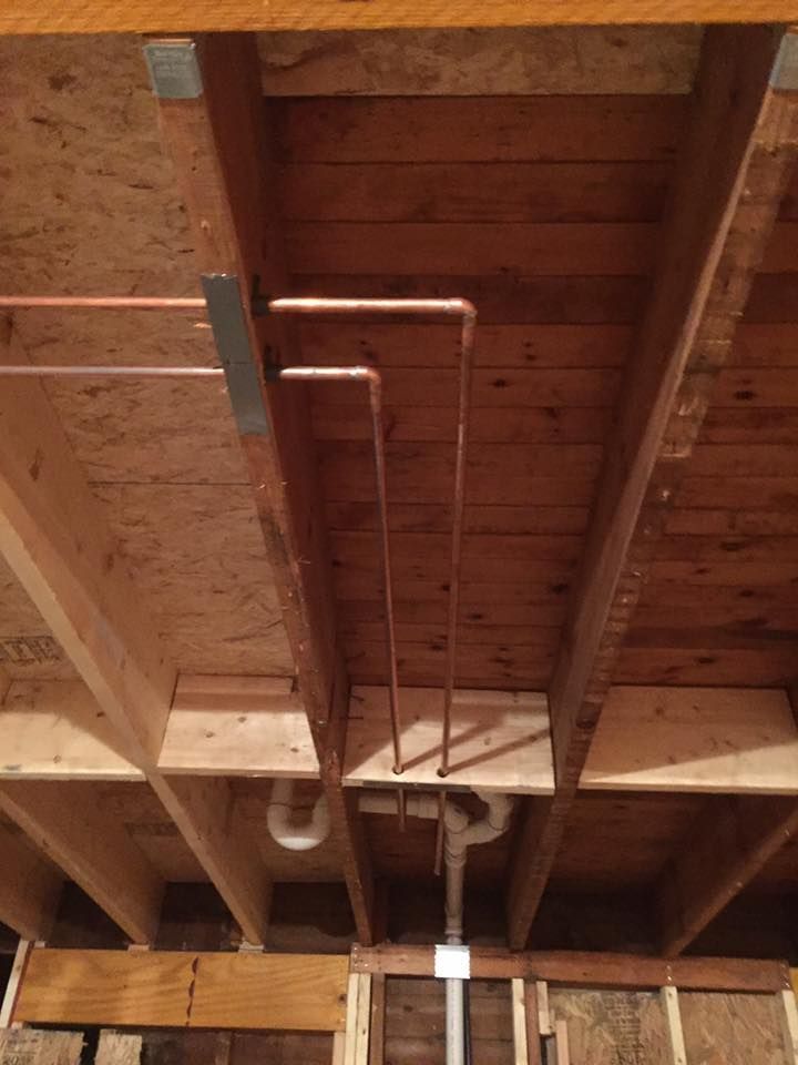 A wooden ceiling with copper pipes hanging from it.