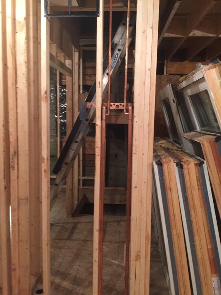 A ladder is hanging from a wooden wall in a building under construction.