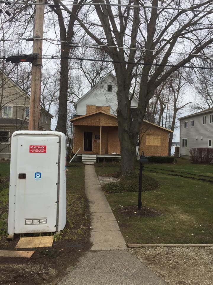 A portable toilet is in front of a house that is being remodeled