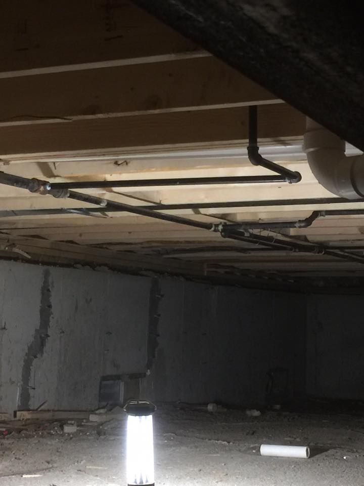 A basement with a lot of pipes and a light on the floor.