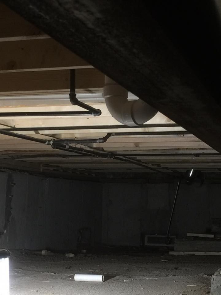 A dark basement with a lot of pipes coming out of the ceiling.