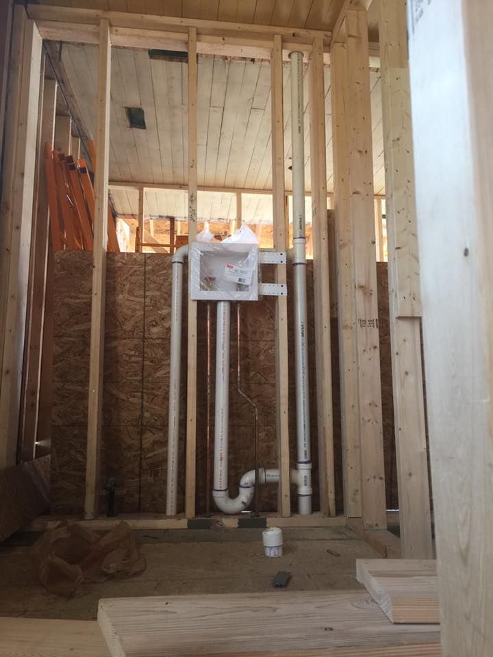 A bathroom under construction with pipes and a box on the wall