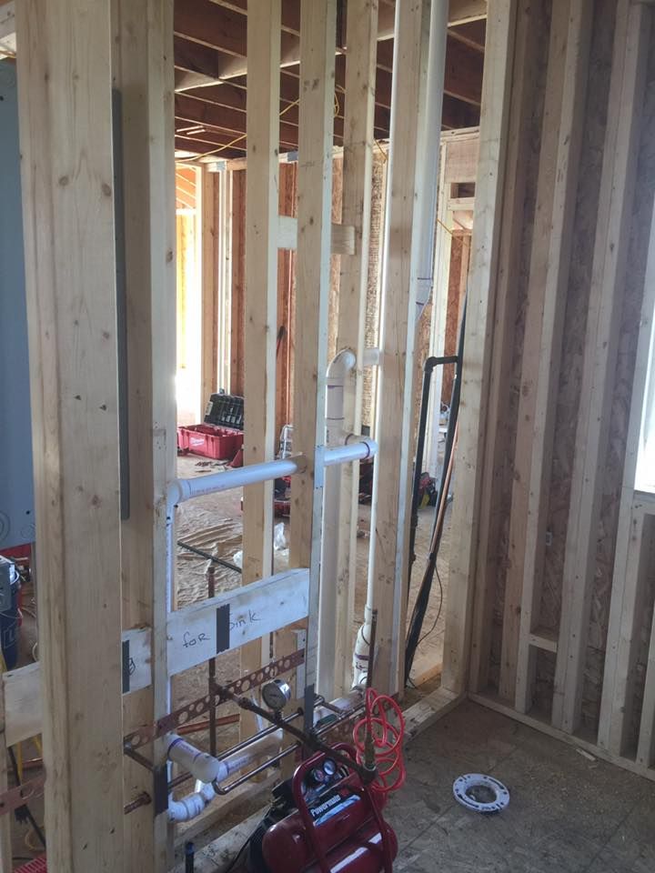 A red air compressor is sitting in a room under construction.