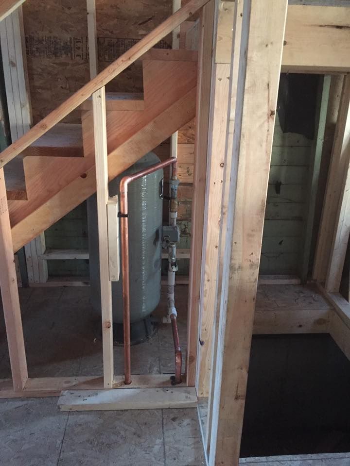 A wooden staircase with copper pipes underneath it