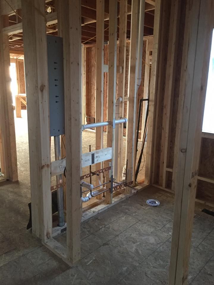 A bathroom in a house under construction with wooden beams and pipes.