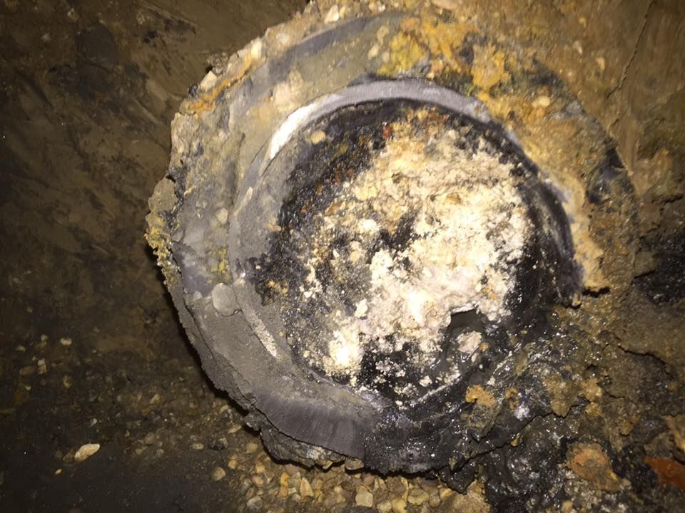 A close up of a dirty pipe in the ground.