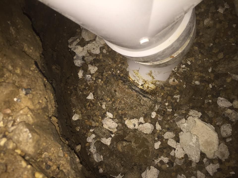 A white pipe is sticking out of a hole in the ground.