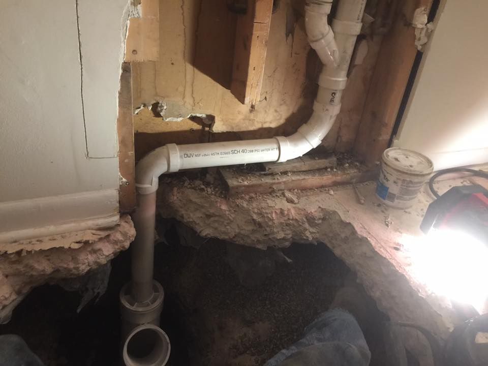 A person is working on a pipe in a basement.