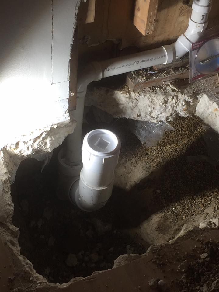 A white pipe is coming out of a hole in the ground.