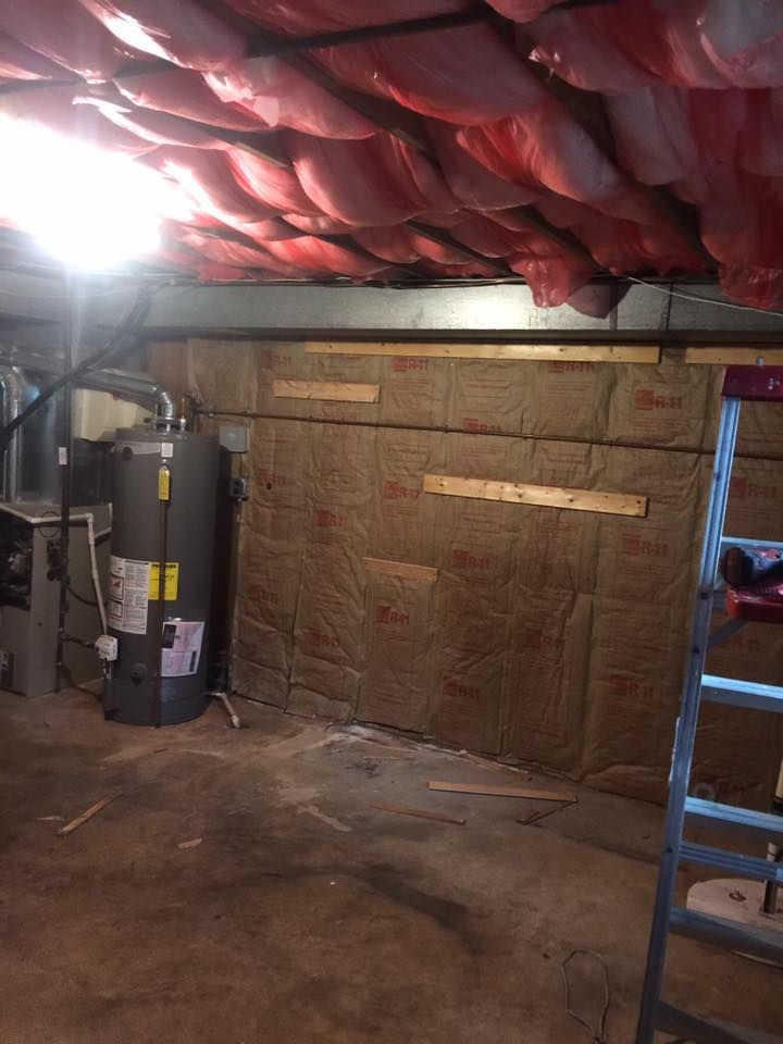 A room with a water heater and a ladder in it.