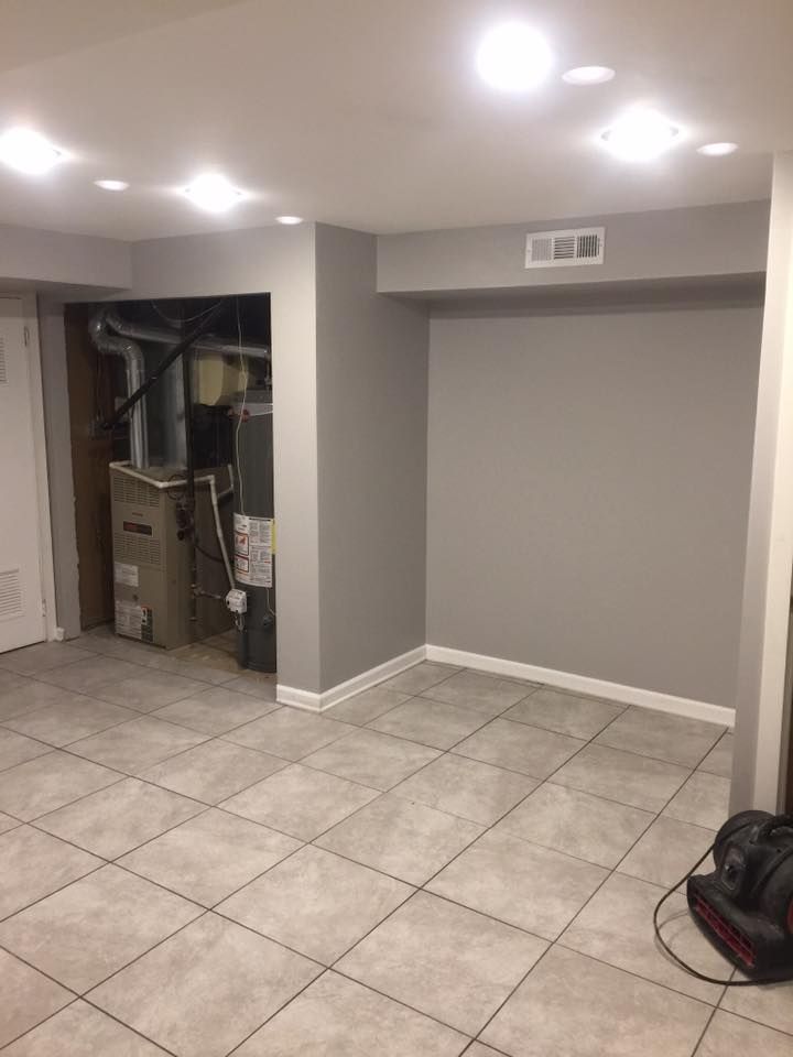 An empty basement with tile floors and gray walls.