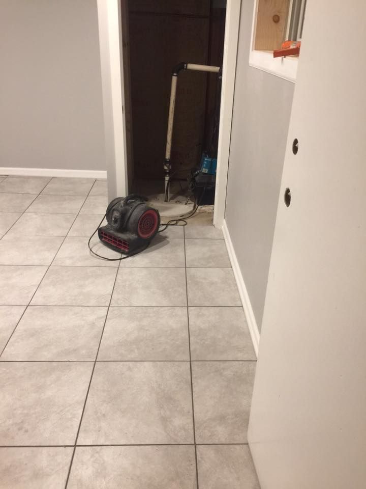 A vacuum cleaner is sitting on a tiled floor in a hallway.