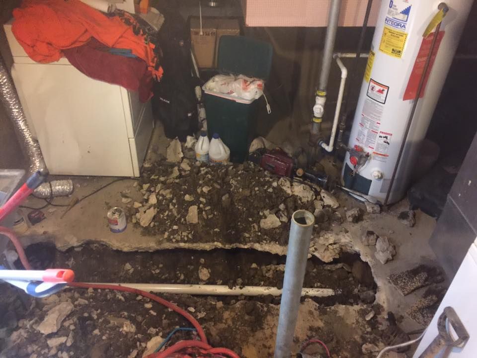 A water heater is being repaired in a basement.