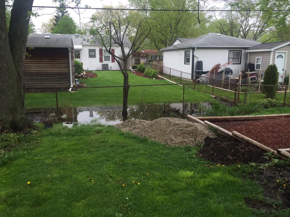 A flooded backyard with a fence and houses in the background