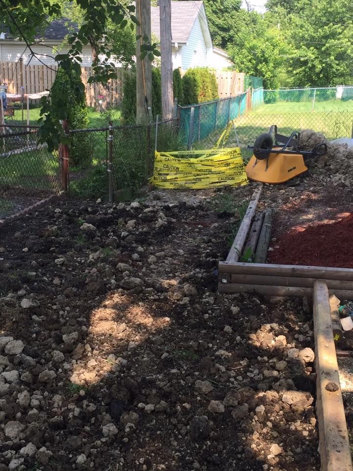 A lawn mower is sitting in the dirt in a backyard.