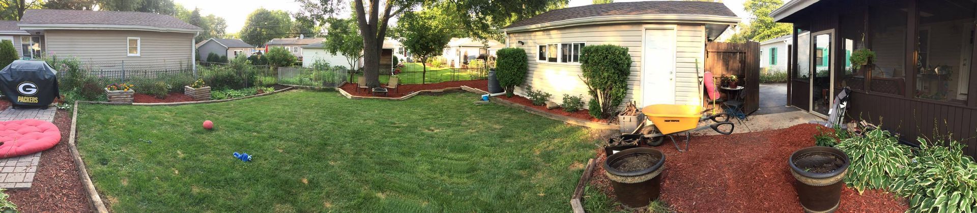 A panoramic view of a backyard with a house in the background.