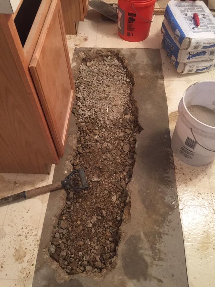 A bucket of cement is sitting on a counter next to a hole in the floor.