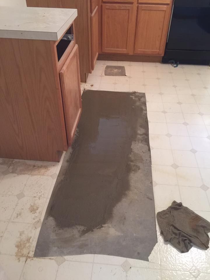 A piece of concrete is laying on the floor in a kitchen.
