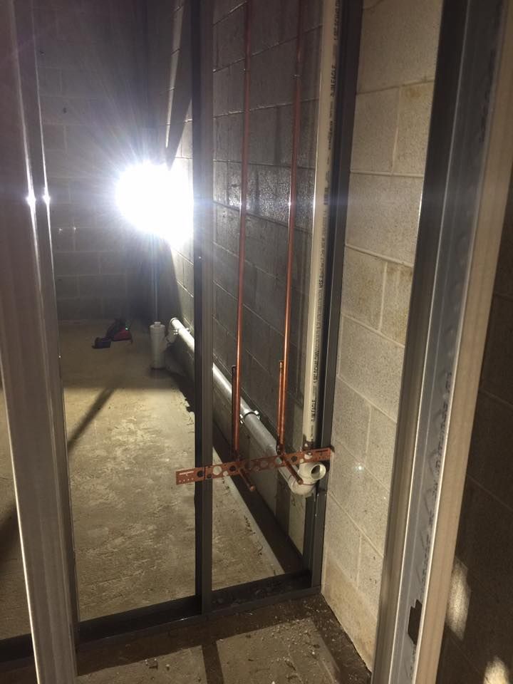 A room with a lot of pipes and a light on the wall.