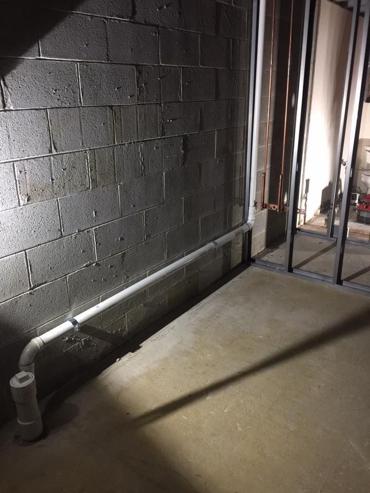 A dark room with a brick wall and a pipe on the floor.