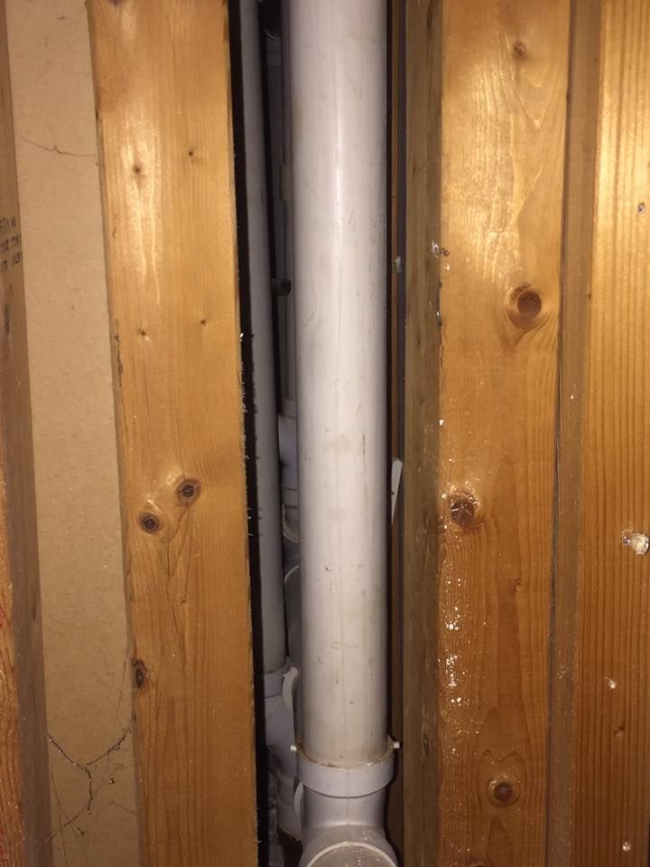 A white pipe is hanging from a wooden wall.