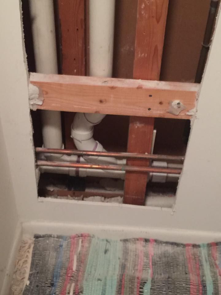 A hole in a wall with pipes coming out of it.
