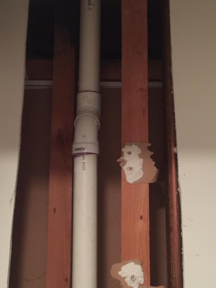 A white pipe is coming out of a hole in a wall.