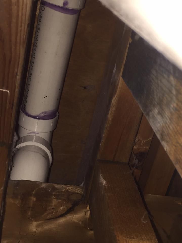 A white pipe is coming out of a hole in a wooden wall.