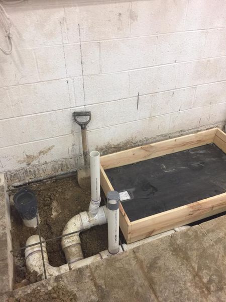 A wooden box is sitting in the dirt next to a pipe and a shovel.