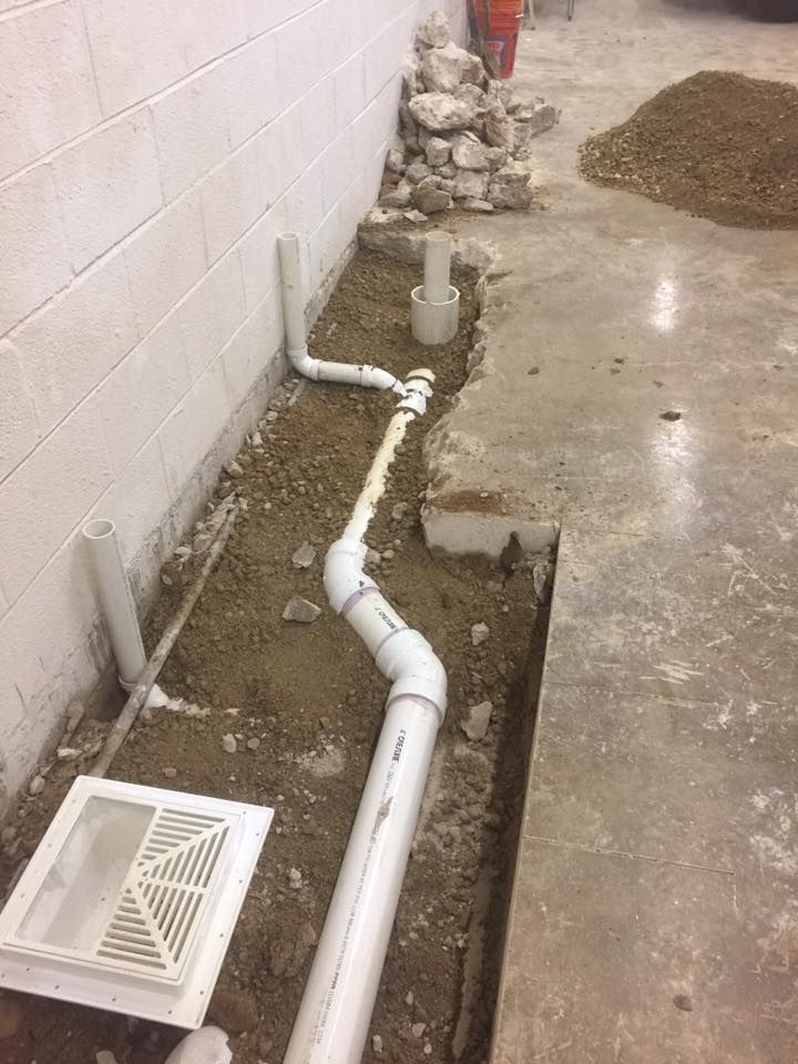 A drain pipe is being installed in a basement.