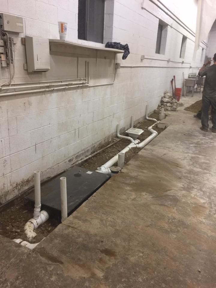 A man is standing next to a wall with pipes coming out of it.