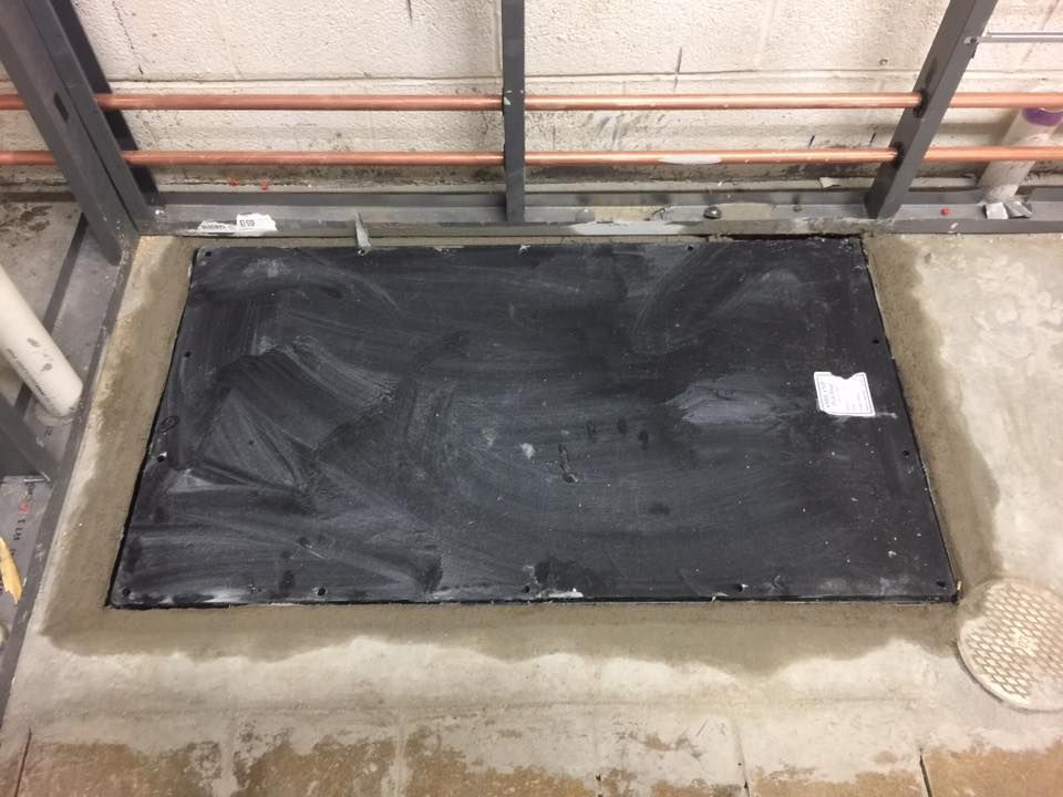 A black door is sitting on a concrete floor next to a wall.