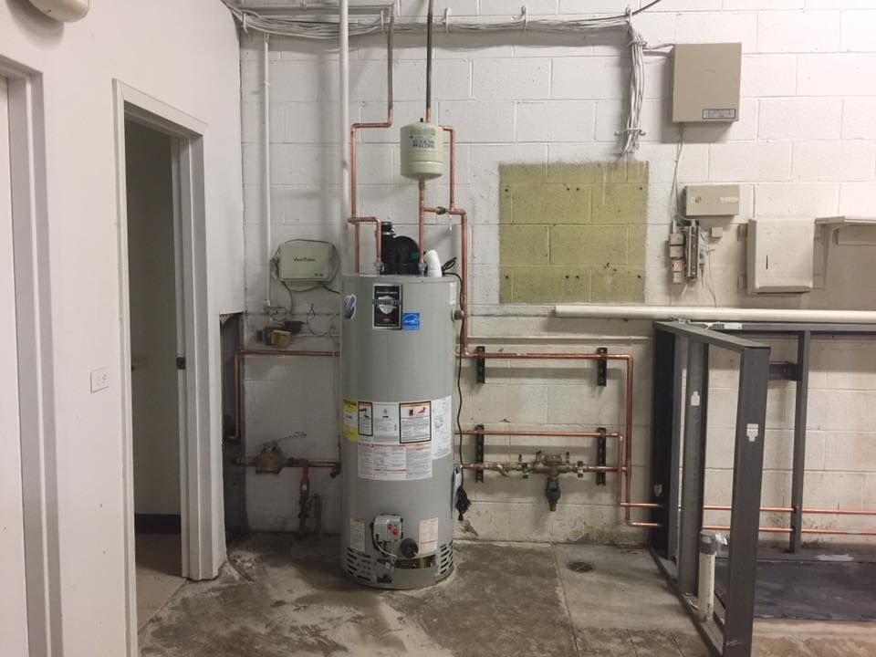 A water heater is sitting in a room next to a door.