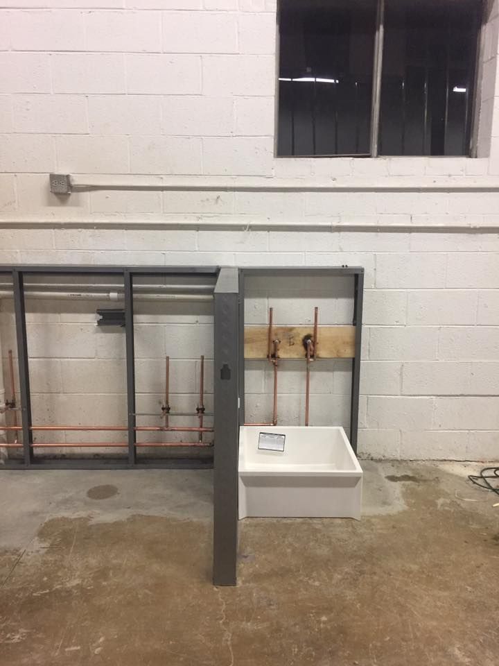 An empty room with a sink and pipes in it