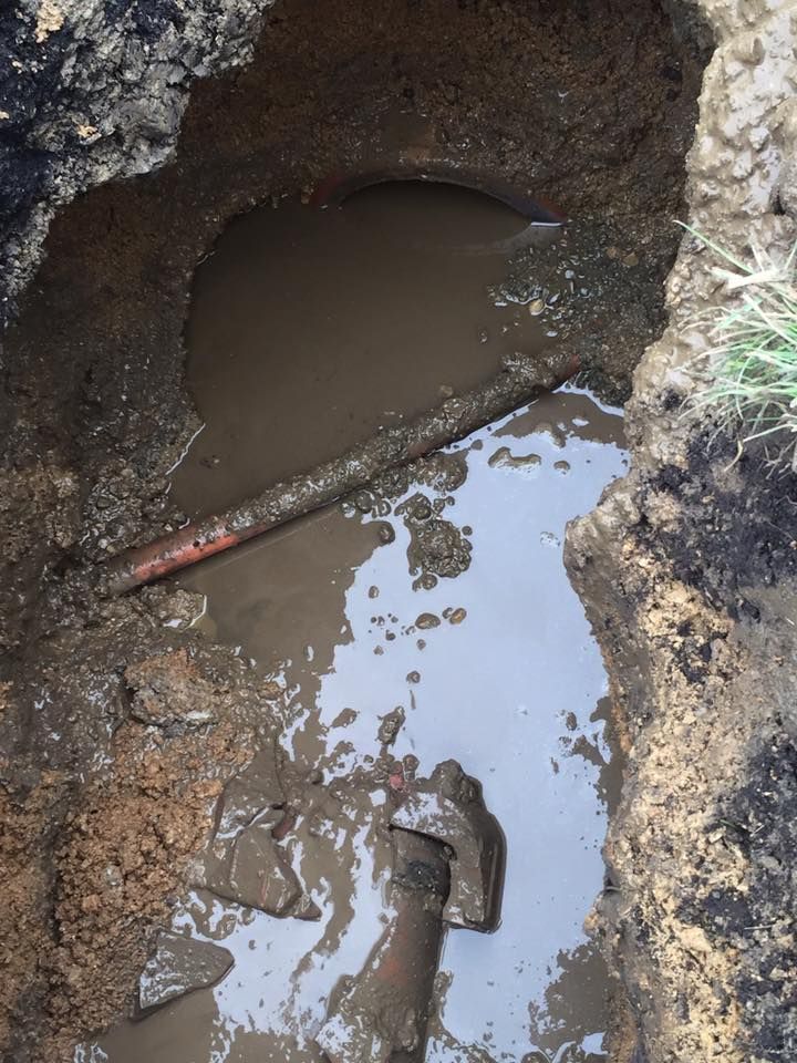 A muddy hole in the ground with a pipe in it