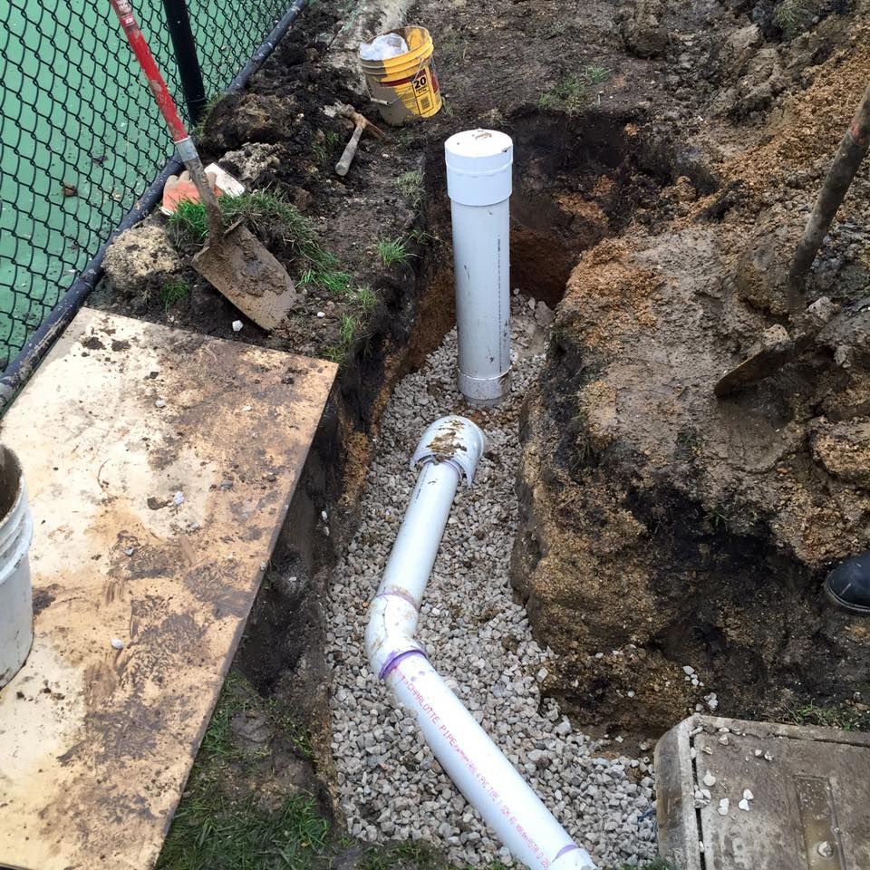 A white pipe is being installed in a hole in the ground