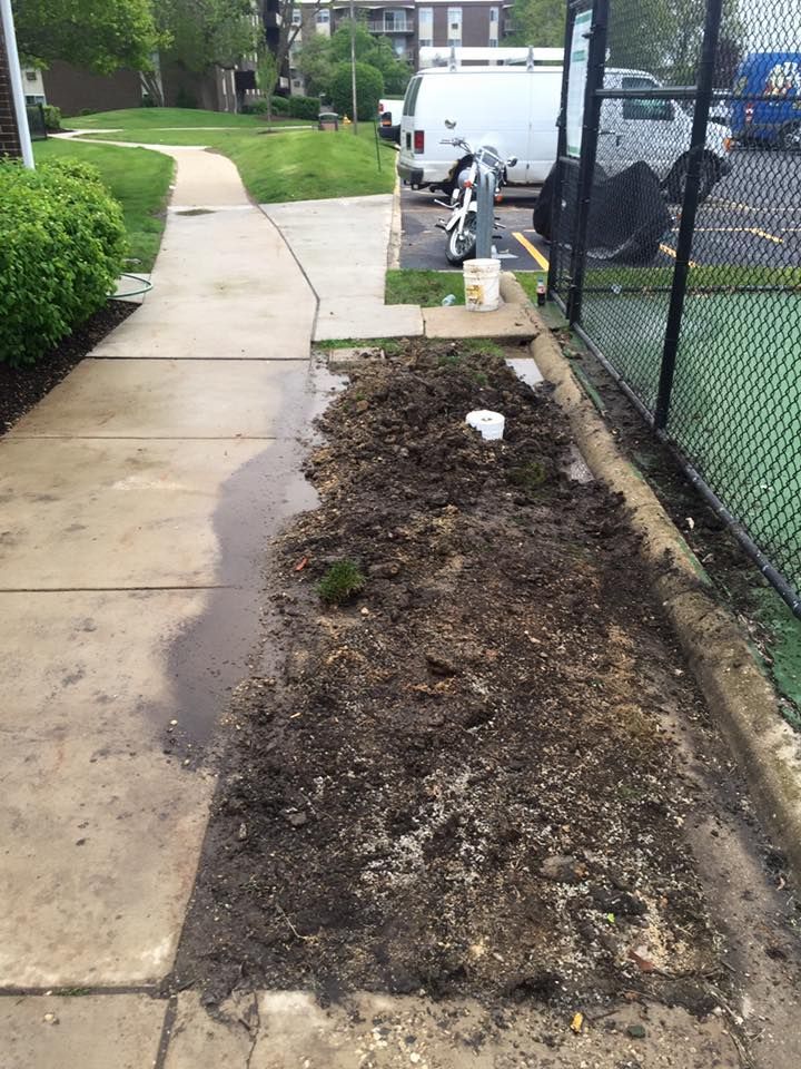 A sidewalk with a lot of dirt on it next to a tennis court.
