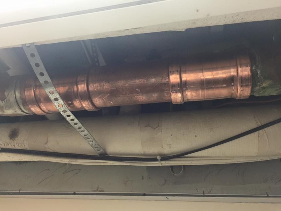 A copper pipe is hanging from the ceiling of a building.
