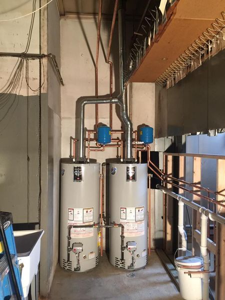 Two water heaters are sitting next to each other in a room.